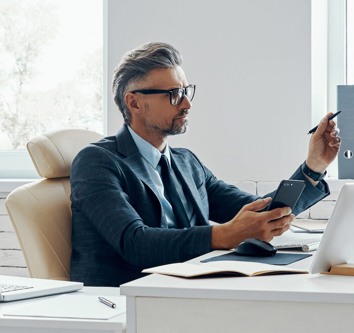 Confident mature man in formal business wear using computer while sitting in office