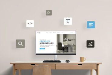 Work desk with computer display featuring web design studio presentation page, surrounded by flying web design icons. Visual representation of a creative digital workspace concept